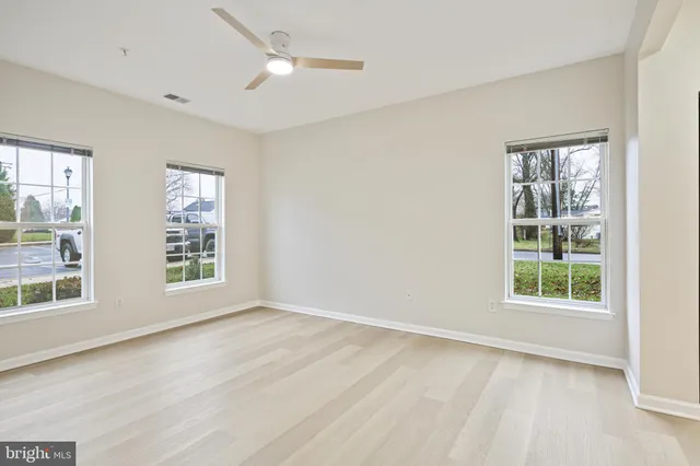 an empty room with wooden floor cabinet and windows