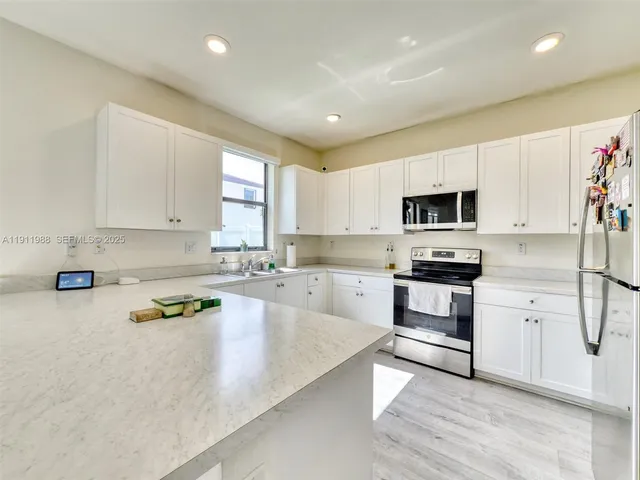 a kitchen with granite countertop white cabinets and appliances