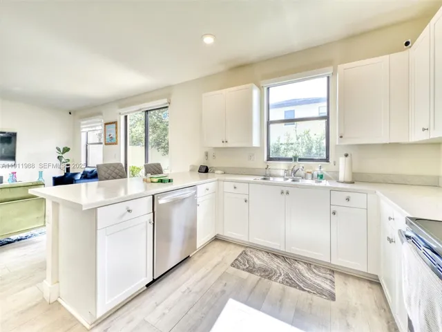 a kitchen with granite countertop white cabinets white appliances a sink and a window