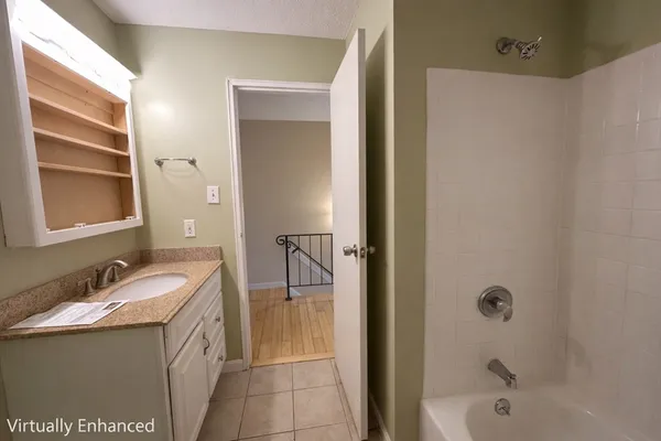 a bathroom with a granite countertop sink a mirror and a bathtub