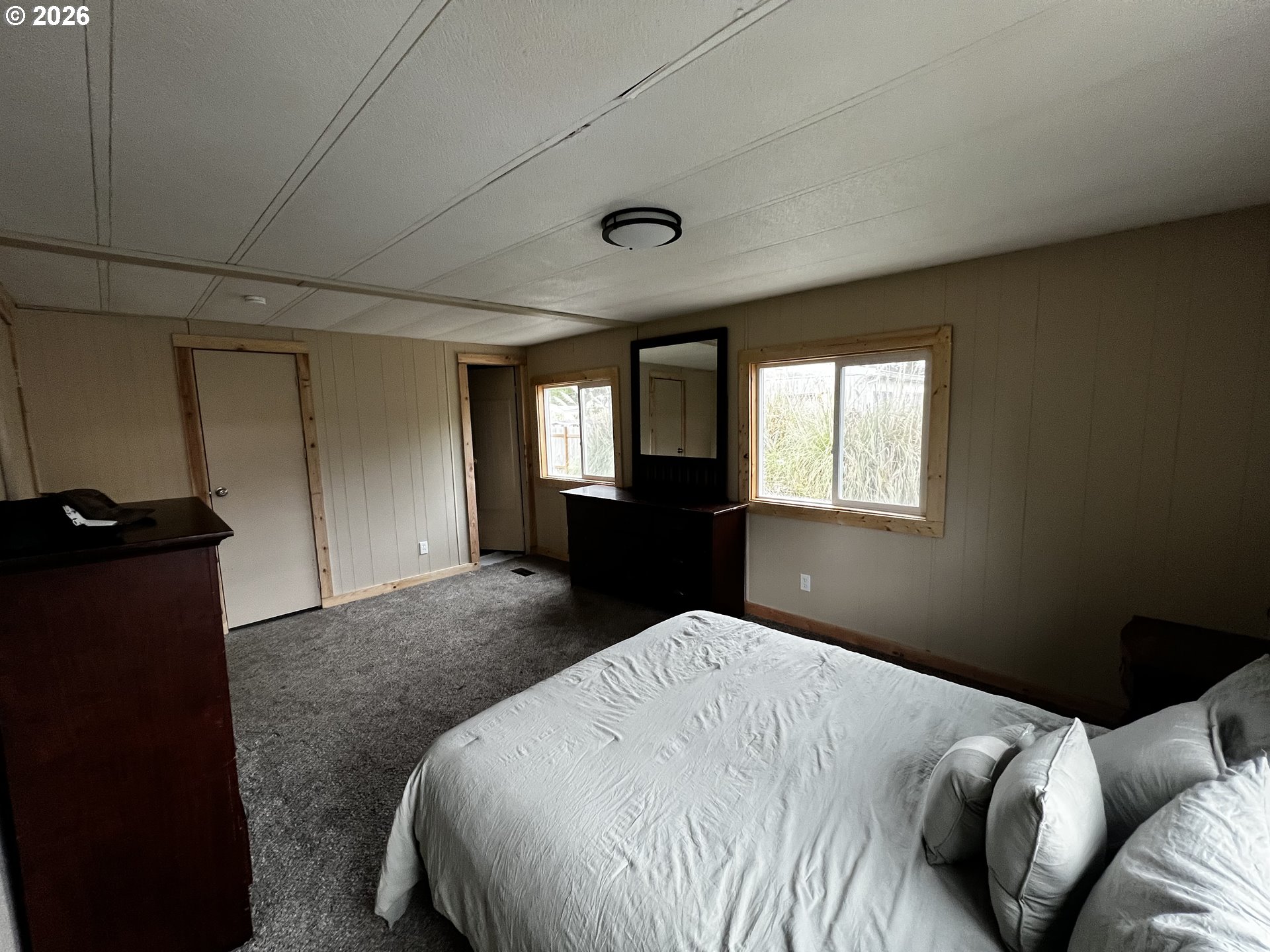 355 North 8th Street Lakeside, OR 97449 - Photo 20 of 22 a bedroom with a bed and a dresser next to a window