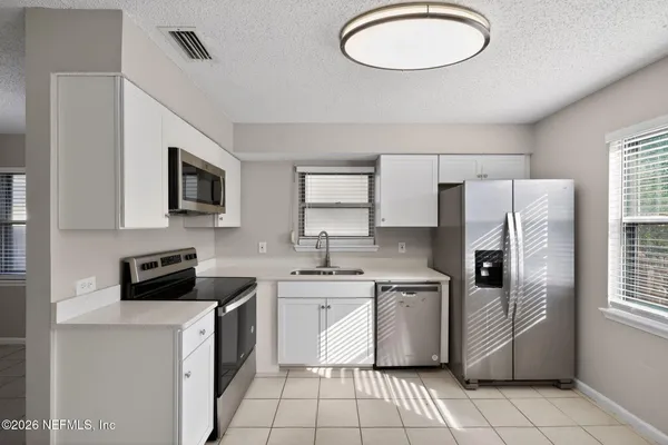 a kitchen with a sink a refrigerator a stove top oven and cabinets