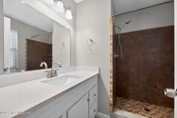 a bathroom with a sink shower and a mirror