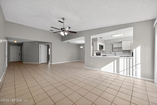 a view of an empty room and kitchen view