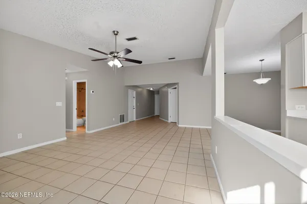 a view of an empty room with a chandelier fan