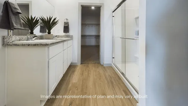 a view of a hallway with wooden floor and a potted plant