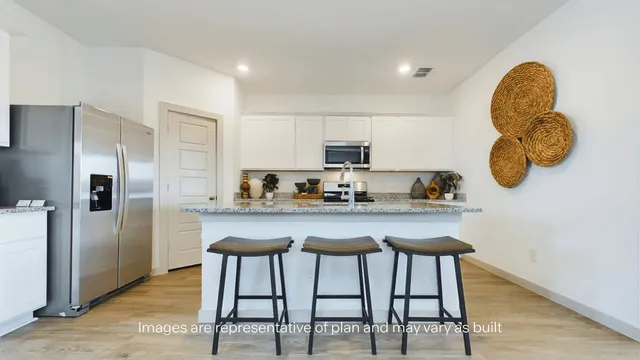 a kitchen with stainless steel appliances granite countertop a table chairs and a refrigerator