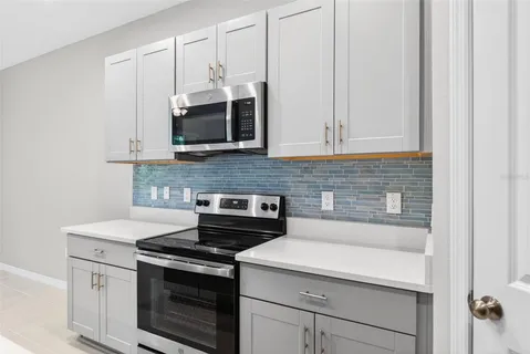 a kitchen with a sink a stove a refrigerator and white cabinets