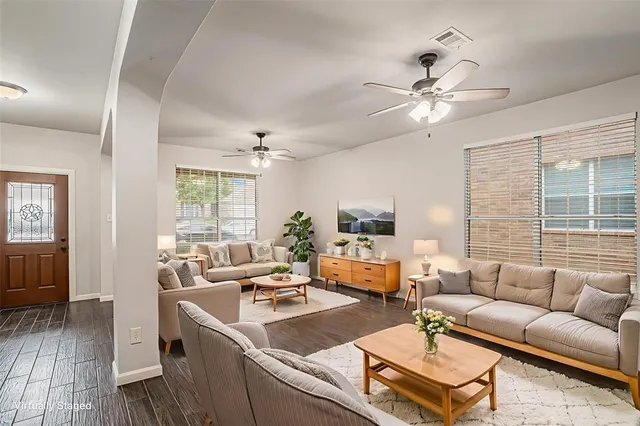a living room with furniture a ceiling fan a fireplace and a window