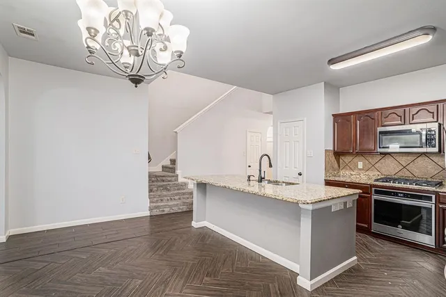 a kitchen with a sink stainless steel appliances a chandelier