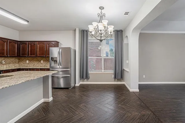 a large kitchen with granite countertop a refrigerator a stove a sink dishwasher with wooden floor and cabinets