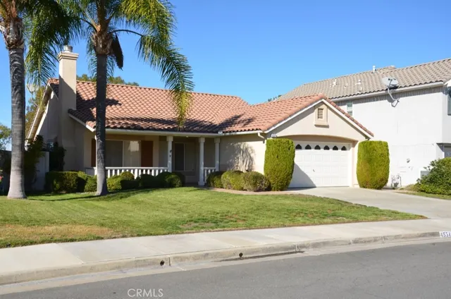 a view of a white house with a small yard and a large parking space
