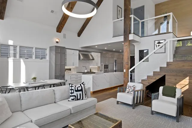 a living room with furniture kitchen view and a large window