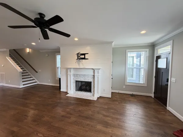 an empty room with wooden floor fireplace and windows