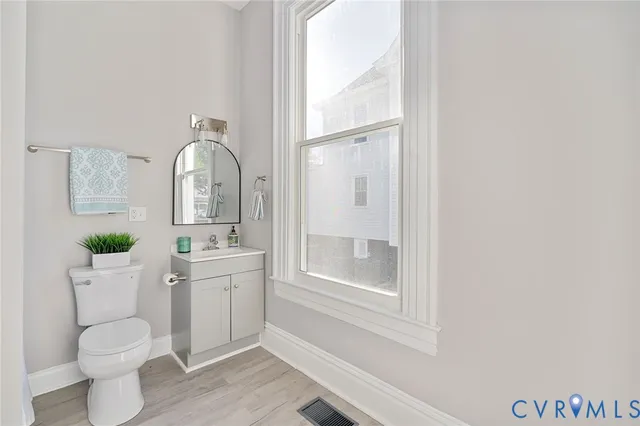 a bathroom with a granite countertop sink vanity mirror and toilet