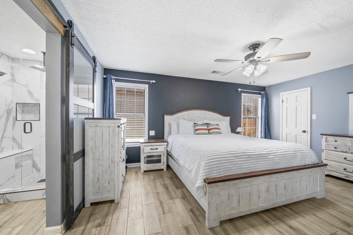 6310 Prairie View Drive Bartlett, TN 38134 - Photo 14 of 27 Bedroom featuring a barn door, wood finish floors, a ceiling fan, a textured ceiling, and multiple windows