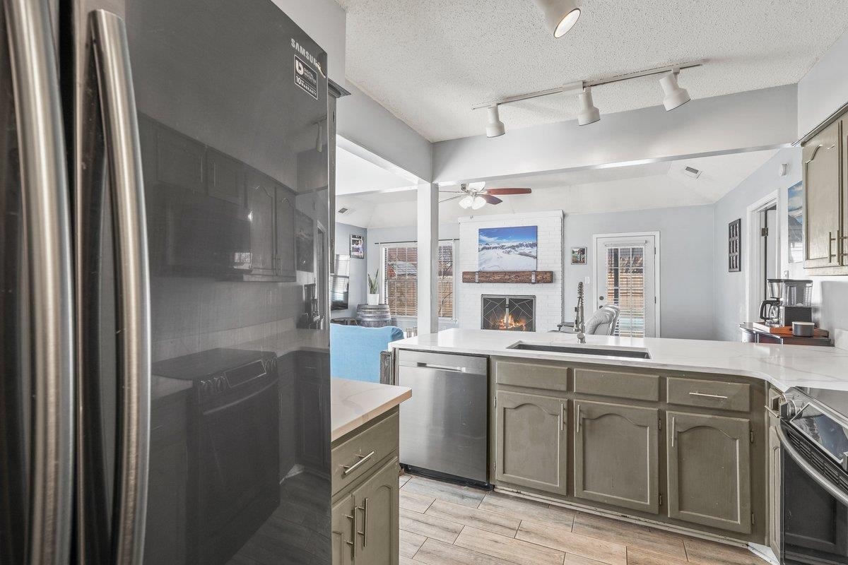 6310 Prairie View Drive Bartlett, TN 38134 - Photo 7 of 27 Kitchen featuring stainless steel appliances, a fireplace, wood finish floors, ceiling fan, and a peninsula