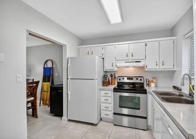 a kitchen with white cabinets and appliances