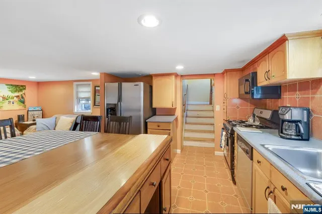a large kitchen with stainless steel appliances wooden floor a stove and a sink