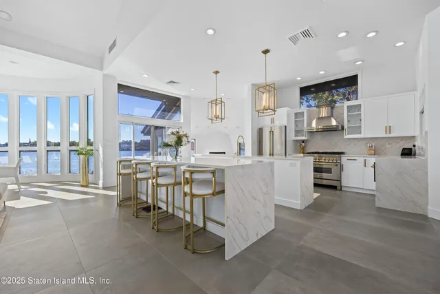 a large white kitchen with lots of counter space and stainless steel appliances
