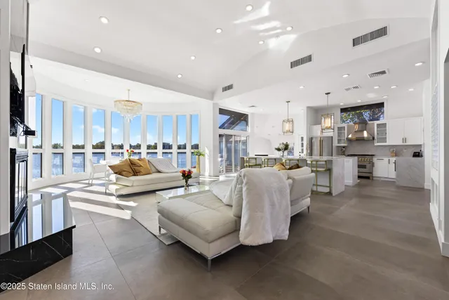 a living room with couches and kitchen view with wooden floor