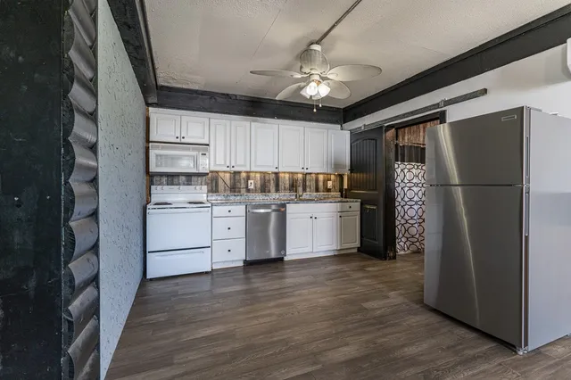 a kitchen with a refrigerator a sink and dishwasher with wooden floor