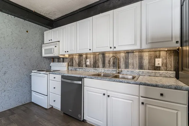 a kitchen with granite countertop white cabinets and white appliances