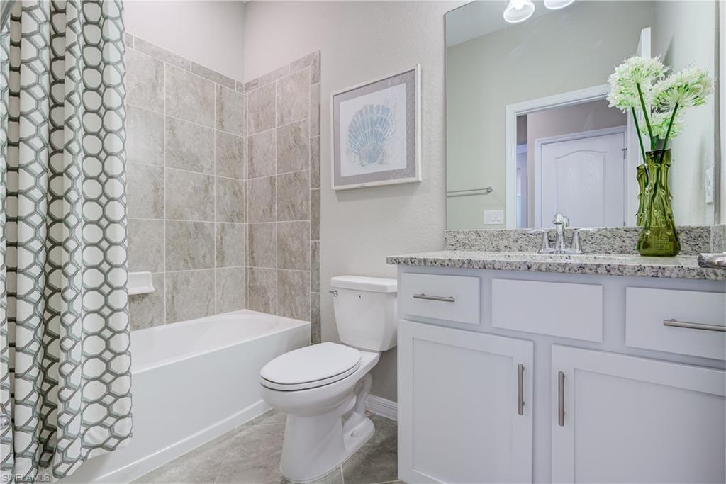 2595 Scarlet Way Naples, FL 34120 - Photo 17 of 27 a bathroom with a granite countertop bathtub sink vanity mirror and toilet