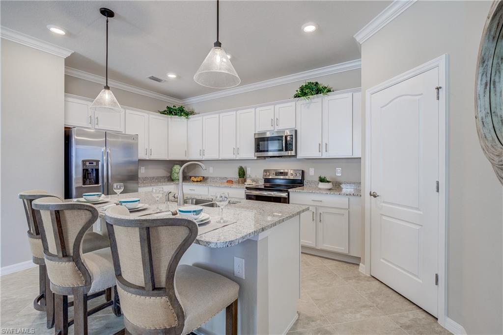 2595 Scarlet Way Naples, FL 34120 - Photo 8 of 27 a kitchen with stainless steel appliances kitchen island a table chairs refrigerator and microwave