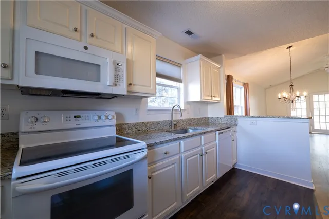 a kitchen with granite countertop a stove microwave and sink