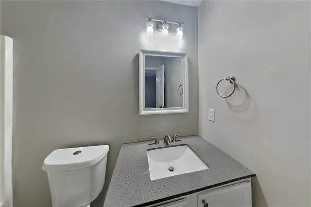 a bathroom with a toilet sink vanity and mirror