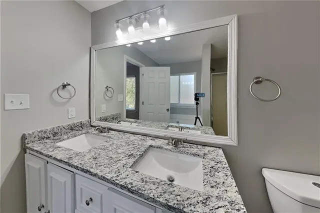 a bathroom with a granite countertop sink a toilet and mirror