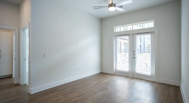 an empty room with wooden floor chandelier fan and windows
