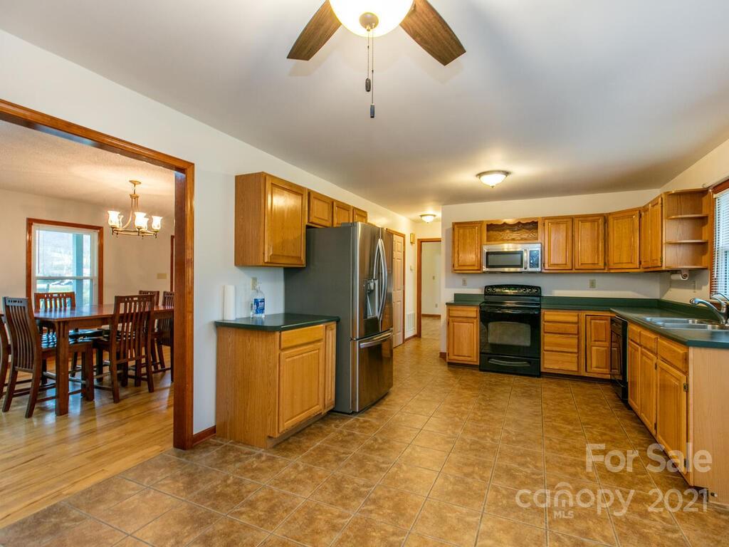 20 Brooks Branch Road Leicester, NC 28748 - Photo 20 of 40 a kitchen with stainless steel appliances kitchen island granite countertop a stove top oven a sink dishwasher a dining table and chairs with wooden floor