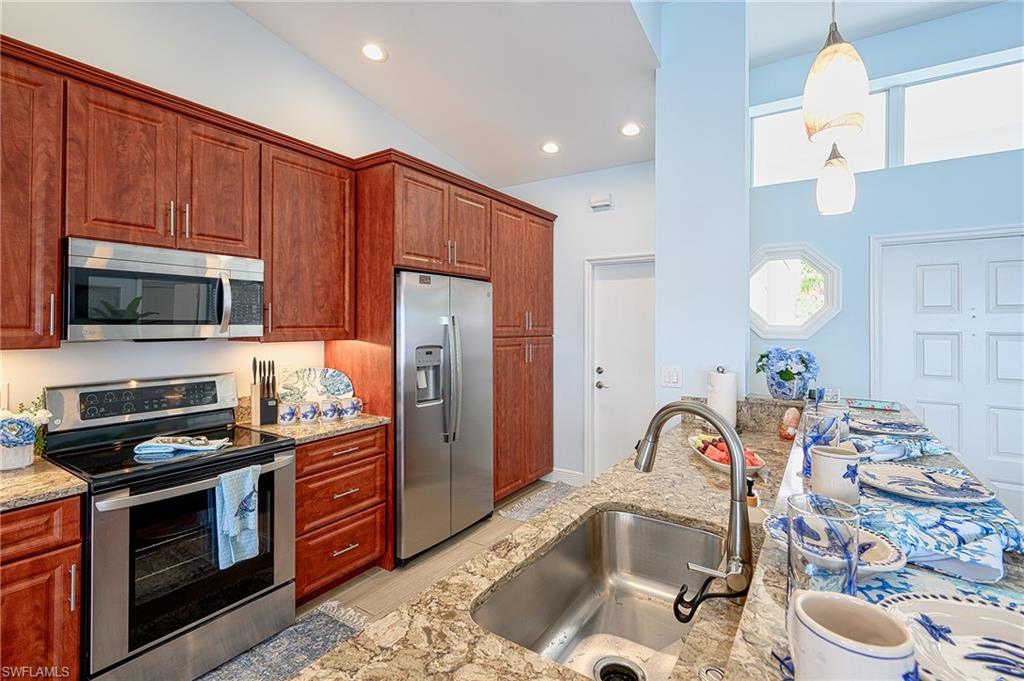 7311 Mill Pond Circle Naples, FL 34109 - Photo 21 of 42 a kitchen with stainless steel appliances granite countertop a sink stove and refrigerator
