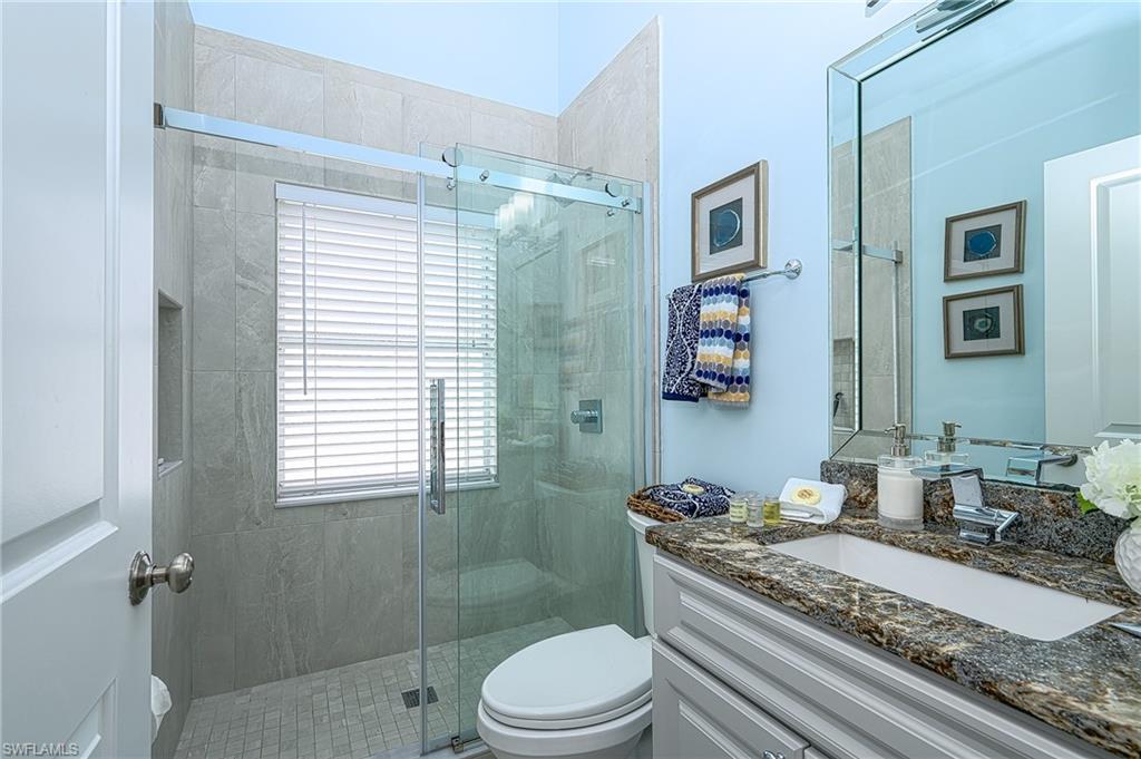 7311 Mill Pond Circle Naples, FL 34109 - Photo 27 of 42 a bathroom with a granite countertop sink toilet a mirror and shower