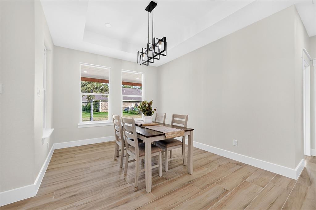120 Springwood Road Enchanted Oaks, TX 75156 - Photo 11 of 37 Tray ceiling with a contemporary black linear chandelier, wood-finish flooring, and multiple windows