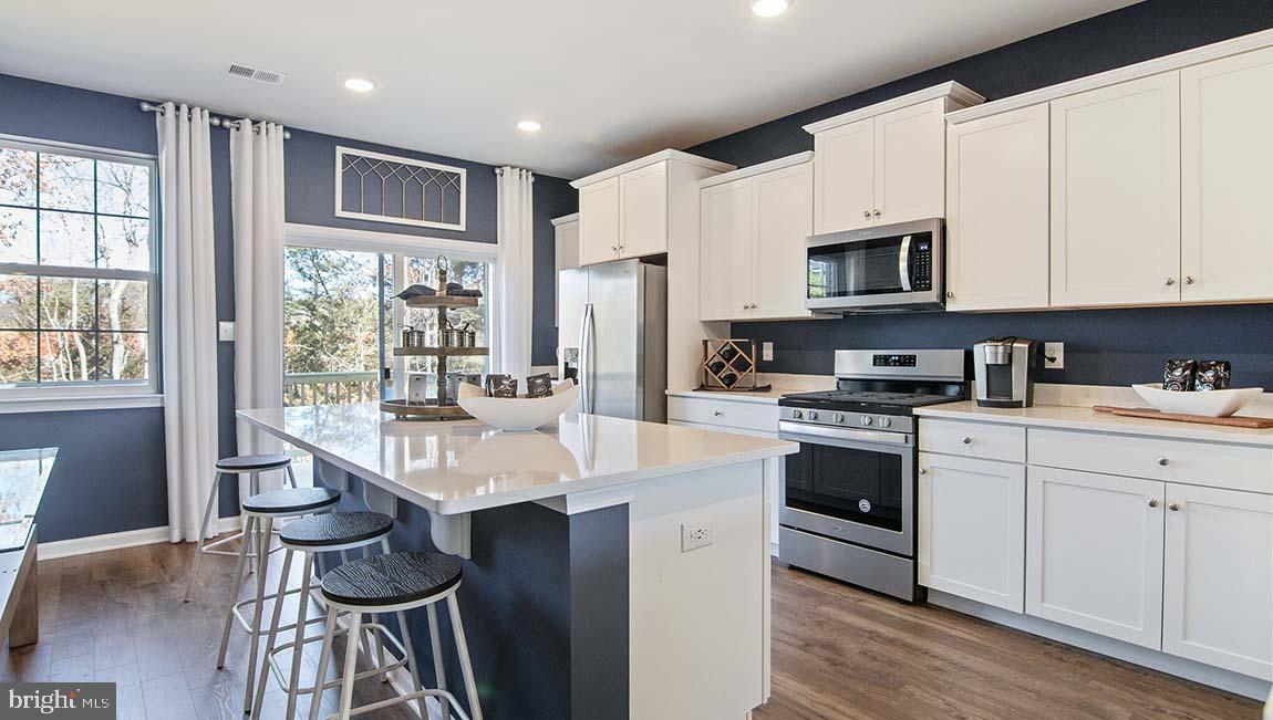 a large white kitchen with stainless steel appliances granite countertop a stove a sink dishwasher a microwave oven and a dining table with wooden cabinet