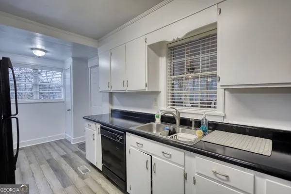 a kitchen with granite countertop stainless steel appliances a sink window and cabinets