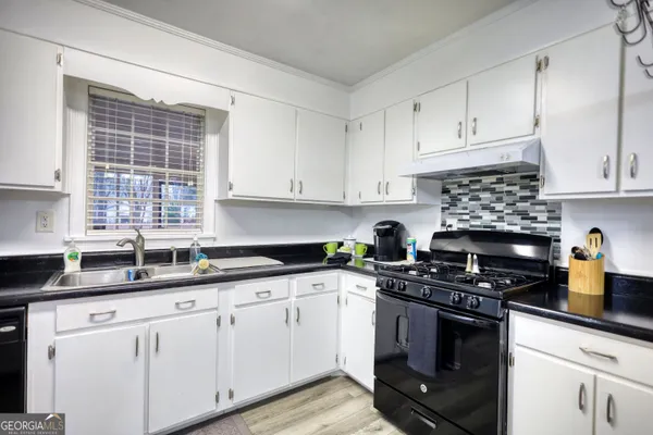 a kitchen with granite countertop white cabinets appliances and a window