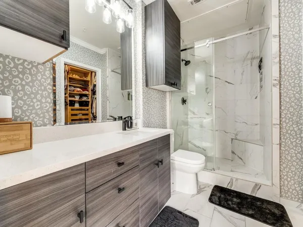 a bathroom with a sink a toilet a shower and a mirror