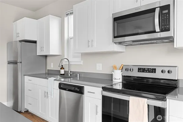 a kitchen with cabinets stainless steel appliances and a wooden floor