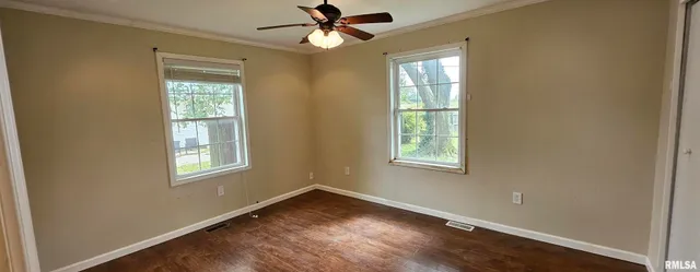 an empty room with wooden floor ceiling fan and windows