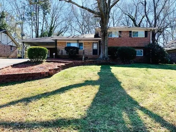 a front view of house with yard and trees in the background