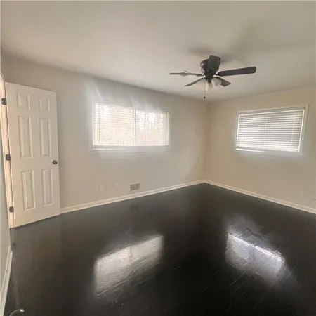 an empty room with wooden floor fan and windows