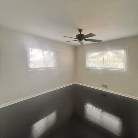 an empty room with wooden floor fan and windows