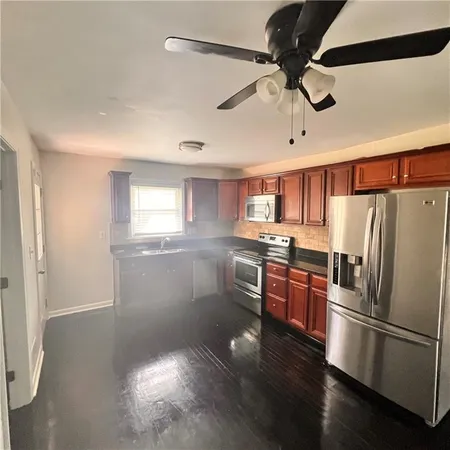 a kitchen with stainless steel appliances granite countertop a refrigerator a sink dishwasher a stove and a refrigerator with wooden floor