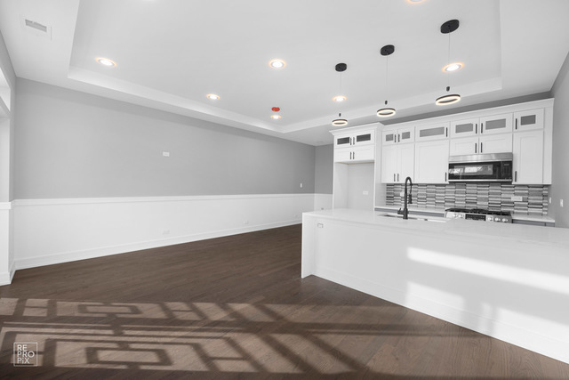 6444 South Evans Avenue, Unit 3 Chicago, IL 60637 - Photo 2 of 6 a large white kitchen with kitchen island a sink stainless steel appliances and cabinets