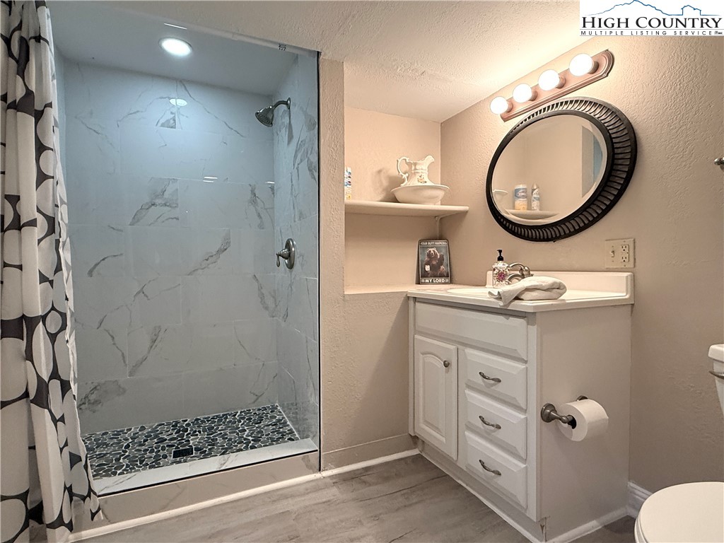 311 Pine Ridge Road Beech Mountain, NC 28604 - Photo 28 of 37 a bathroom with a granite countertop sink a mirror and a shower