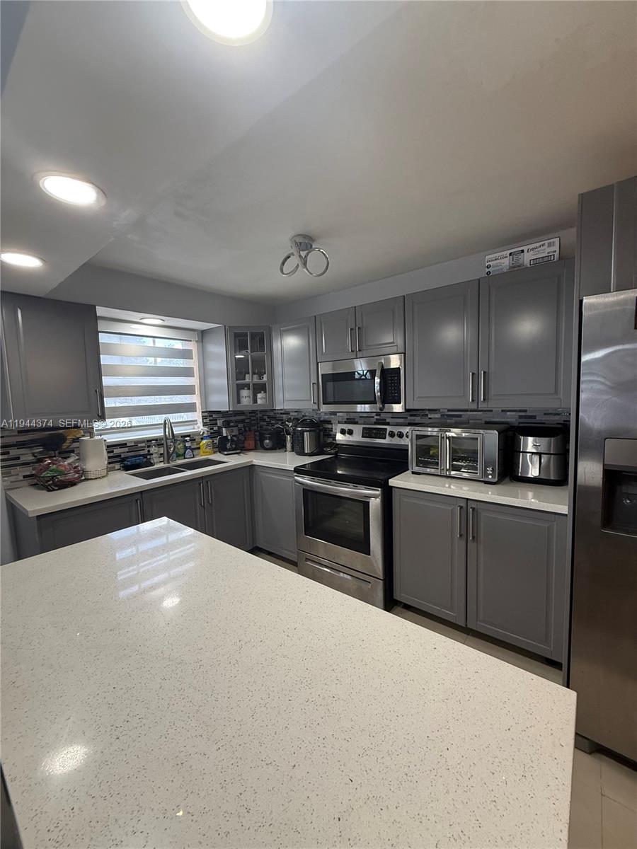 775 East 31st Street Hialeah, FL 33013 - Photo 3 of 11 a large white kitchen with stainless steel appliances granite countertop a stove a sink a refrigerator and white cabinets
